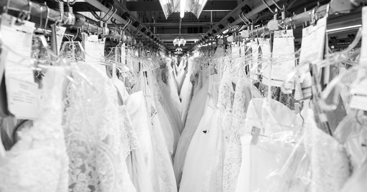 Wedding dresses are neatly hung on racks in our storage and preservation facility. Each dress is carefully protected with tags and clear coverings, reflecting meticulous attention to detail and care in organizing the gowns.